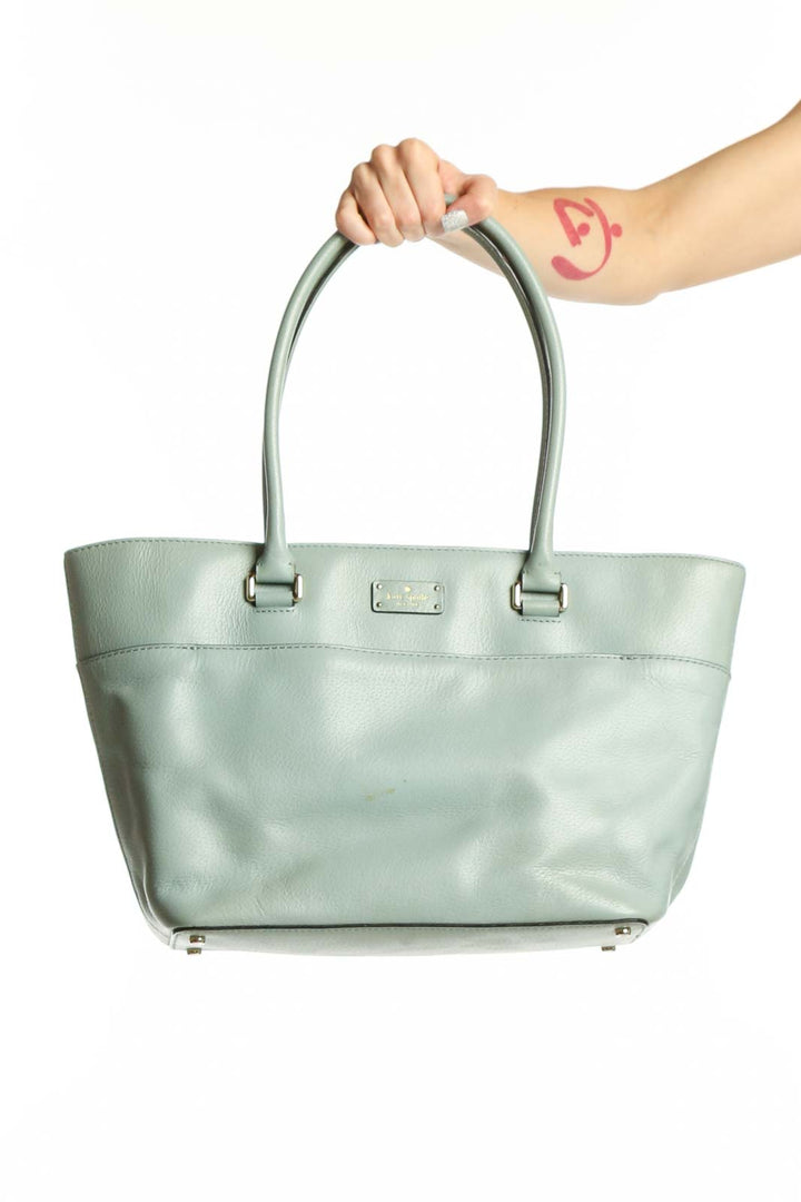 Mint green Kate Spade tote bag with dual handles and signature nameplate, held by model