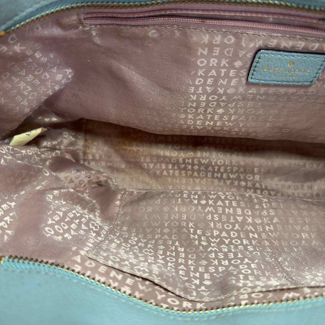 Tag view of mint green Kate Spade tote bag worn by model, showing structured design and handles