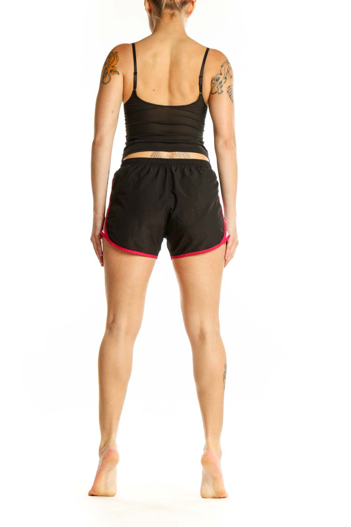 Black Nike athletic shorts with pink trim, back view displaying fit and athletic design