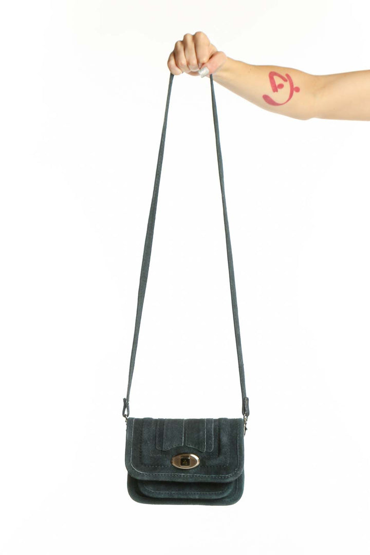 Teal cotton crossbody bag with gold-tone turnlock closure and adjustable strap, held by hand