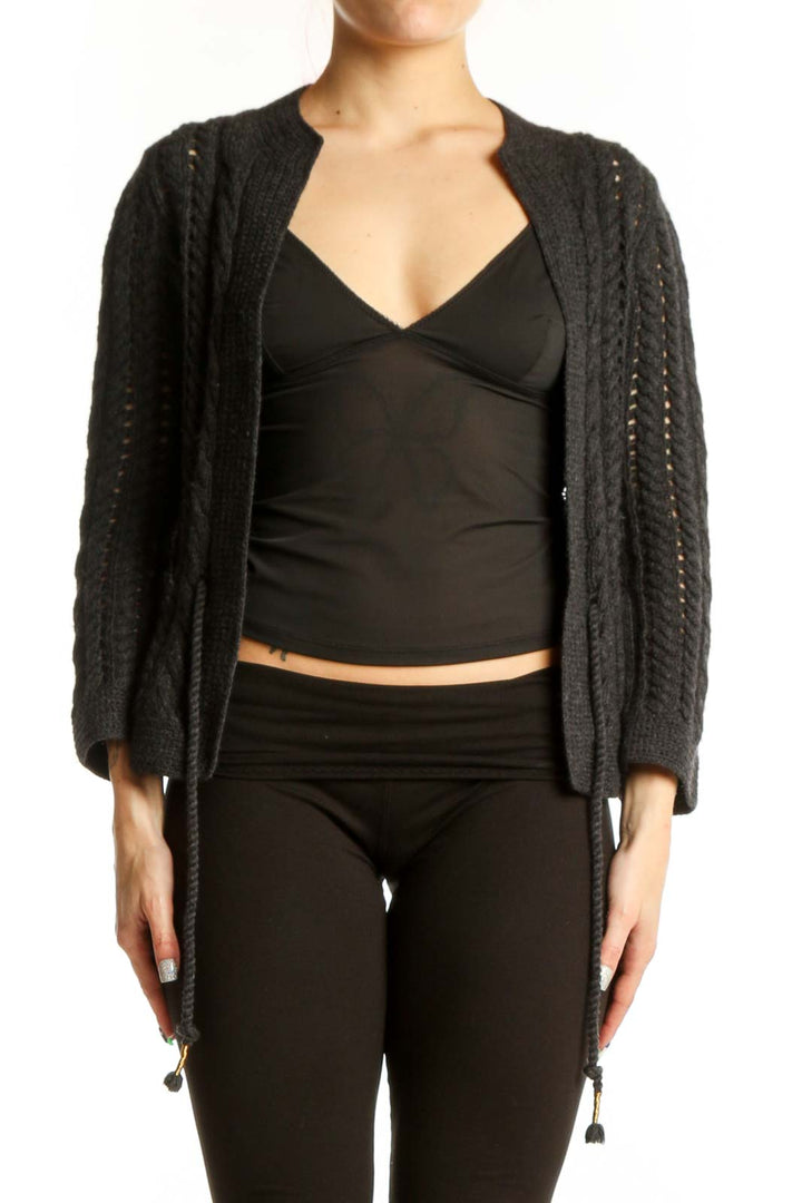 Charcoal cable knit cardigan with open front and tassel tie details, worn over black top