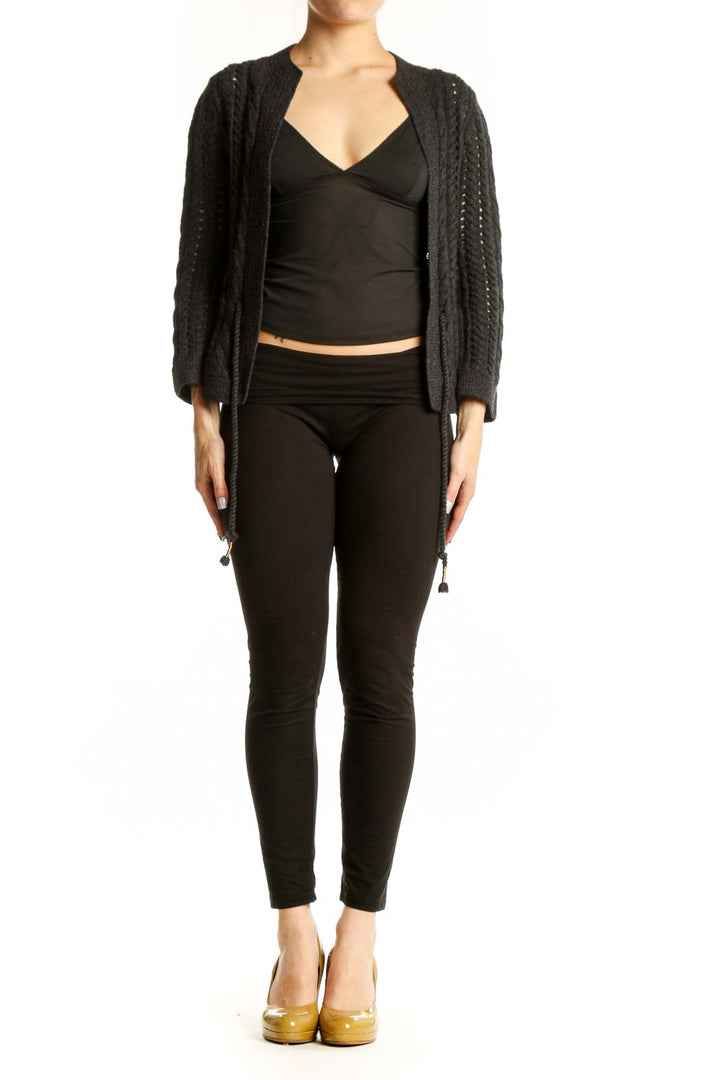 Charcoal cable knit cardigan with open front and tassel tie details, worn over black top