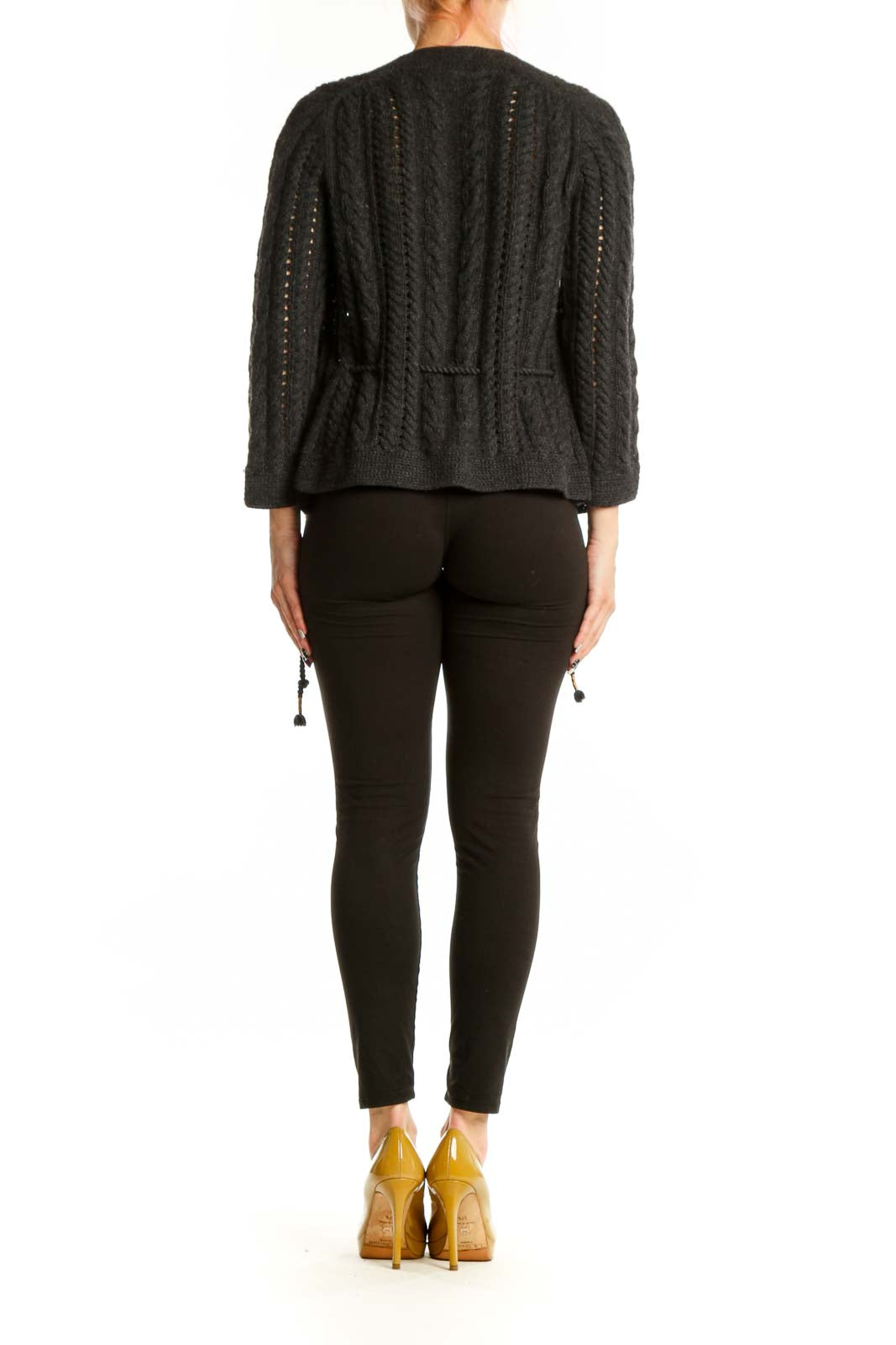 Back view of charcoal cable knit cardigan showing relaxed fit and tassel hem detail