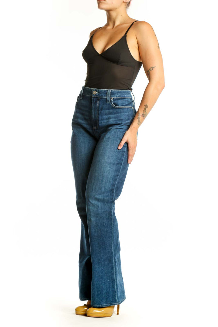 Woman wearing blue high-waisted flare denim jeans by Paige, front view