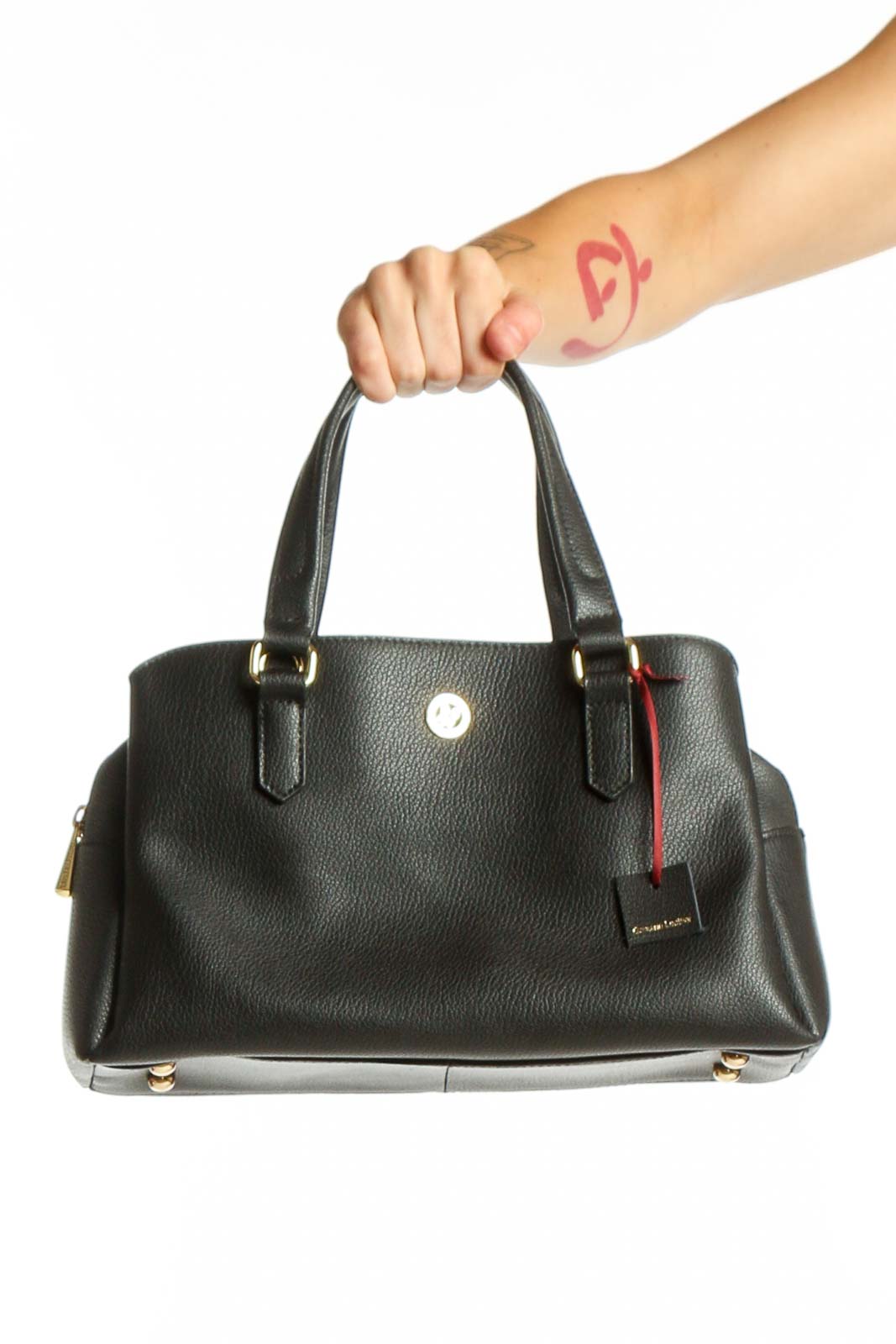 Black leather satchel bag with dual handles and red trim detail held by hand, showing front view with gold-tone hardware