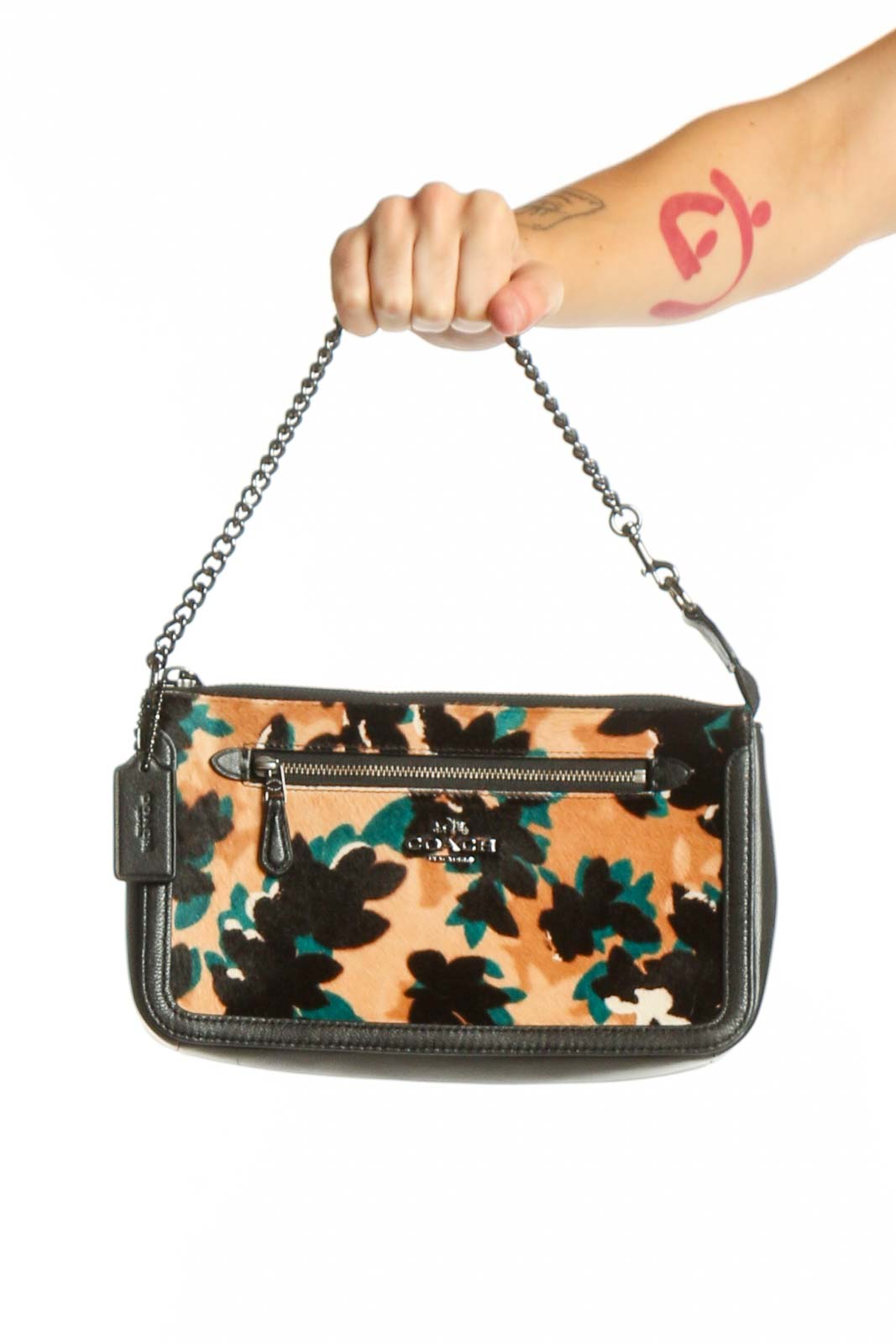 Coach multicolor floral shoulder bag with black leather trim and silver chain straps, held by hand