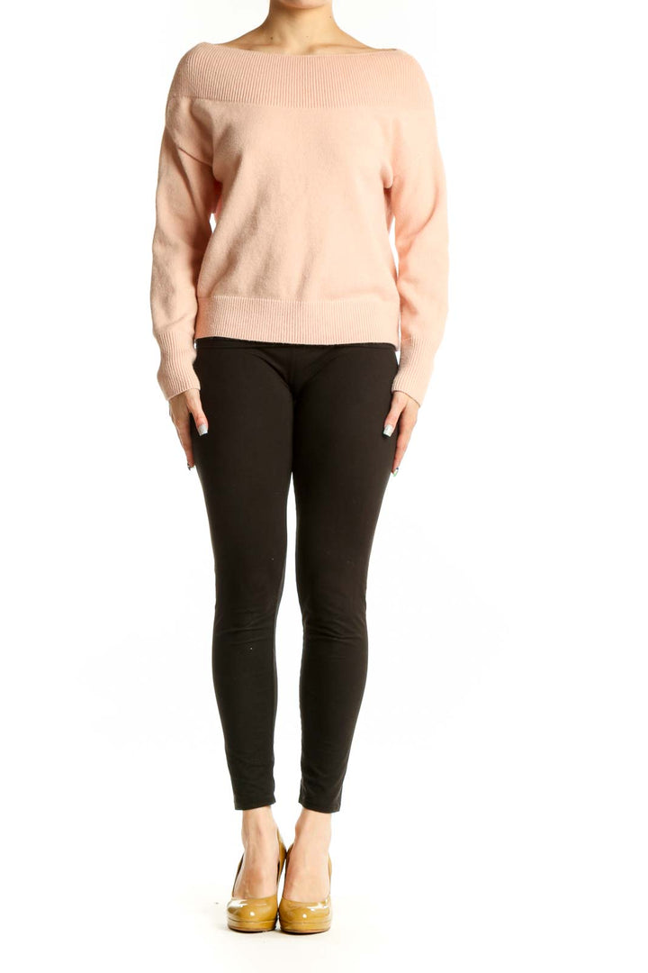 Blush pink ribbed knit pullover sweater with crew neckline and cropped length, styled with black pants