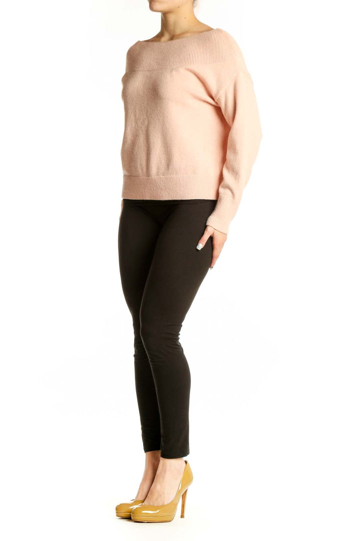 Blush pink ribbed knit pullover sweater with crew neckline and cropped length, styled with black pants