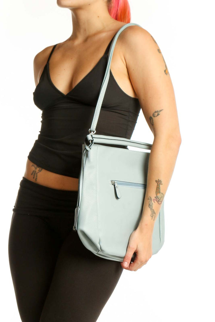 Sage green crossbody bag by David Jones Paris with adjustable strap and front zip pocket, held by hand