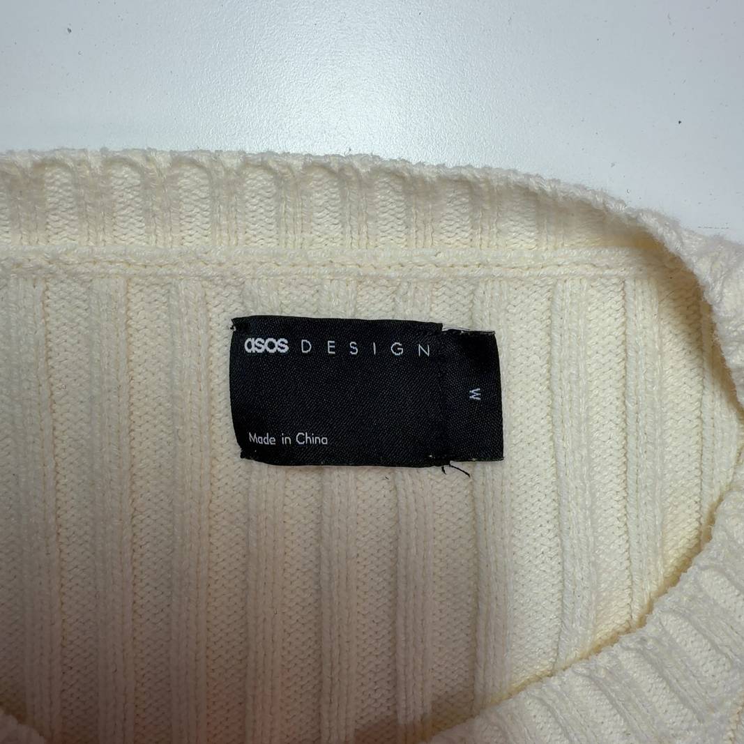 Tag view of cream ribbed knit cropped cardigan showing textured knit pattern and cropped length