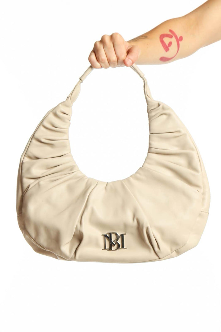 Cream Badgley Mischka ruched shoulder bag with BM logo, held by model showing front hobo design