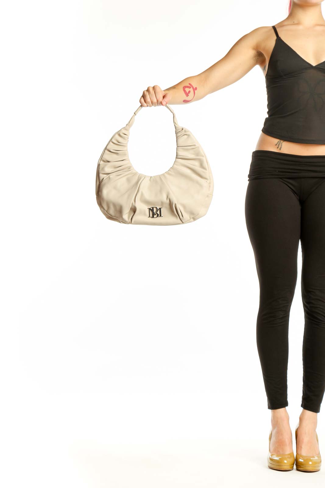 Cream Badgley Mischka ruched shoulder bag with BM logo, held by model showing front hobo design