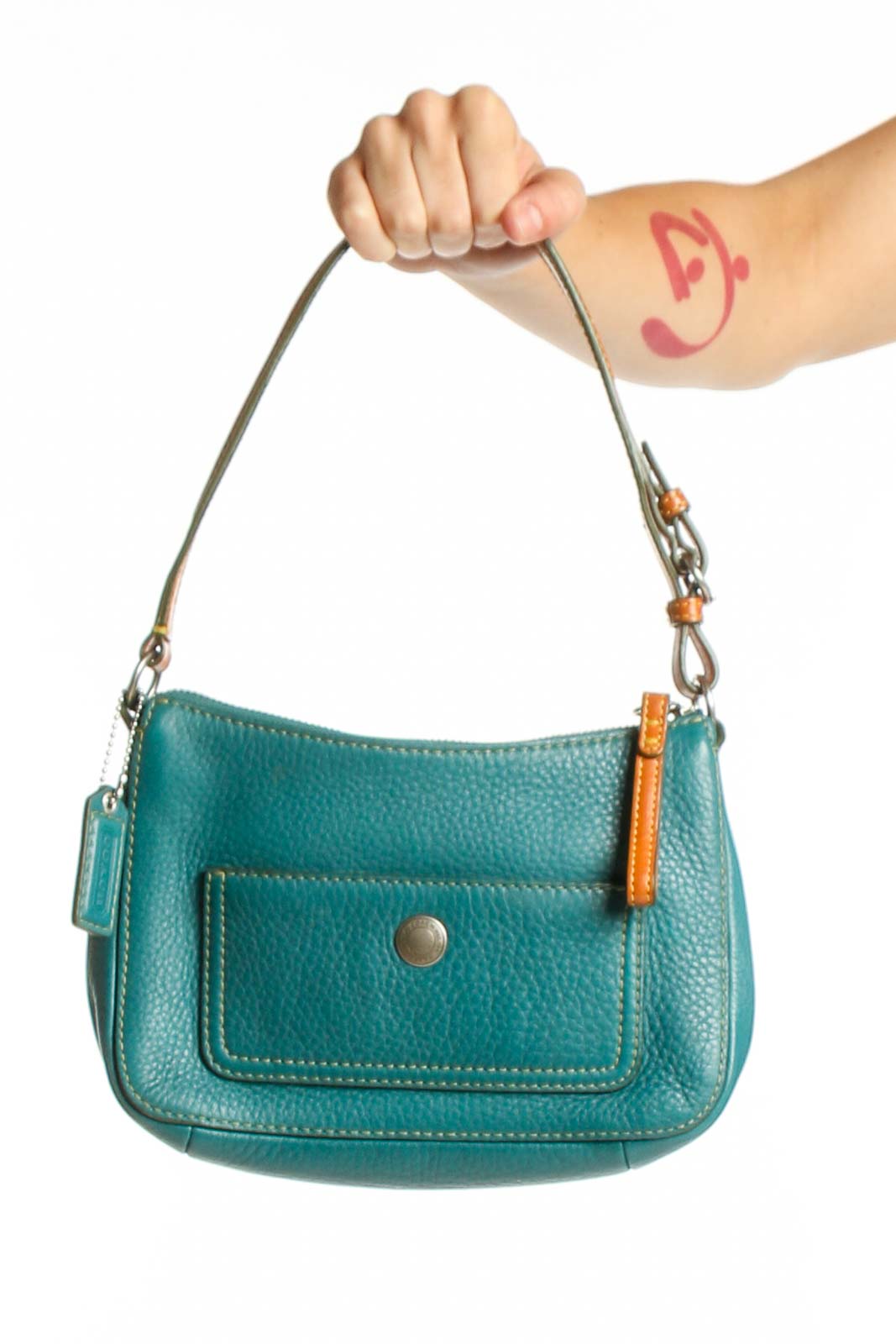 Teal pebbled leather Coach shoulder bag with adjustable strap and front flap pocket, held by hand