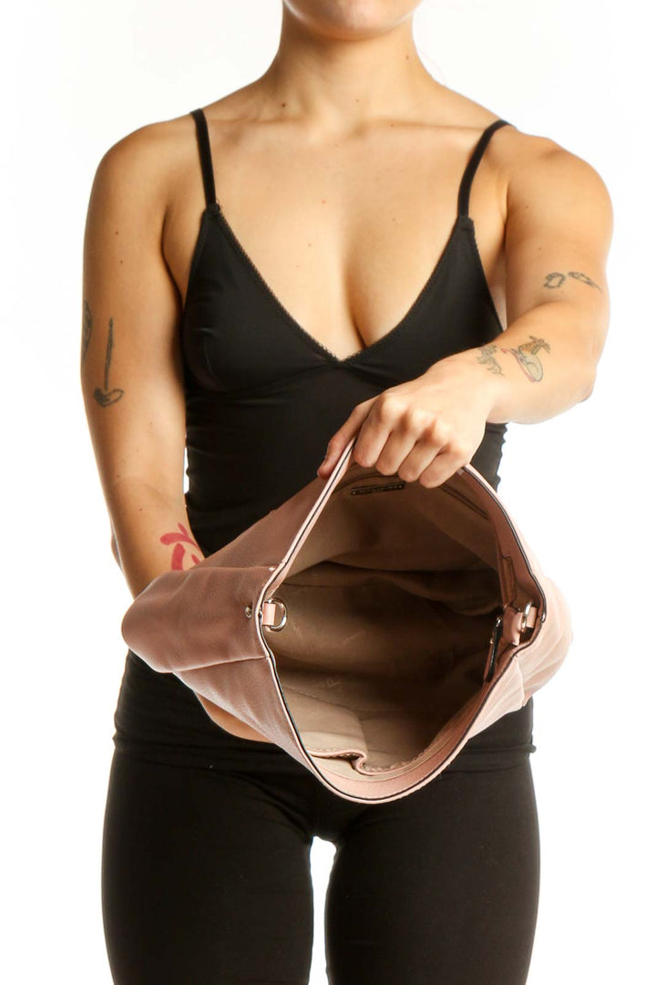 Blush pink leather crossbody bag worn as crossbody style with adjustable strap across body