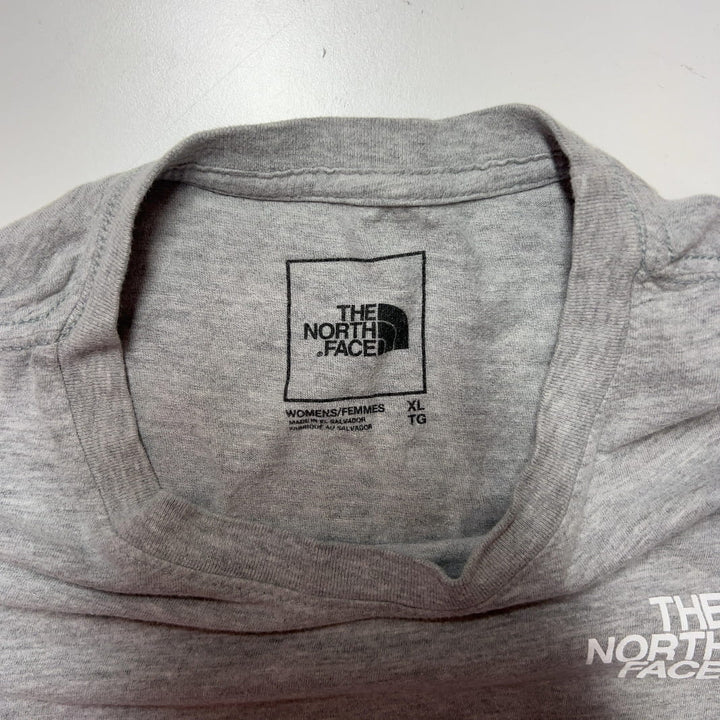 Tag view of gray long sleeve The North Face top showing white logo, paired with black leggings