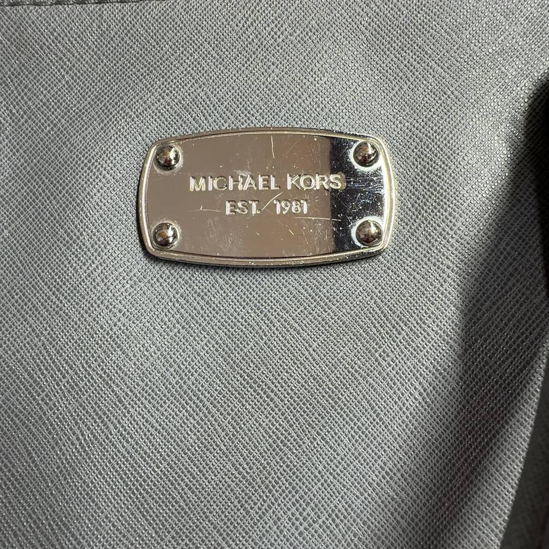 Gray Michael Kors dome tote bag displayed on model, side view showing structured silhouette