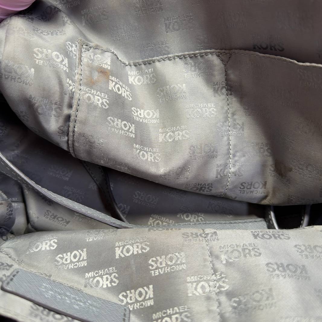 Gray Michael Kors dome tote bag displayed on model, side view showing structured silhouette