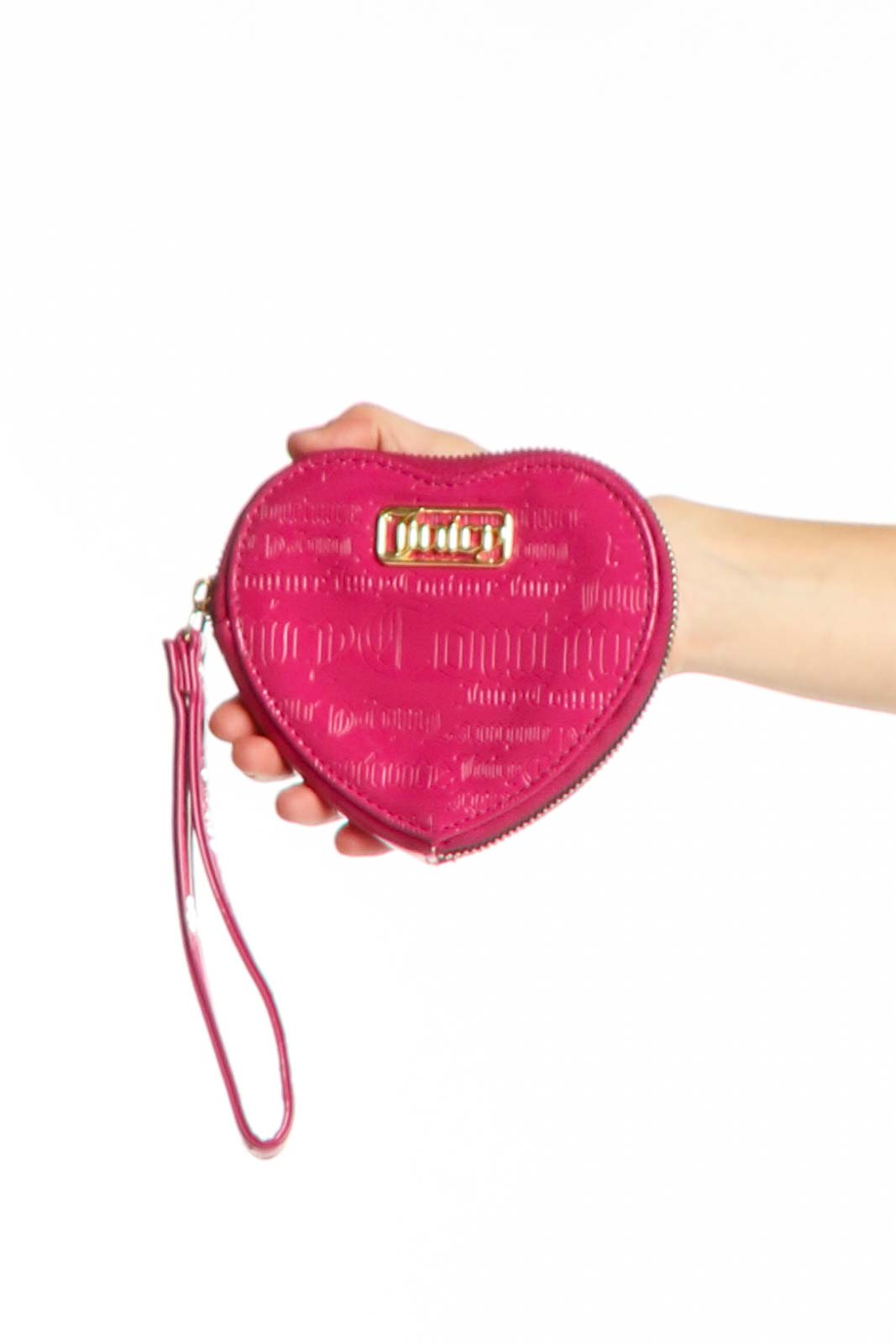 Pink heart-shaped Juicy Couture clutch with quilted texture and wrist strap held in hand