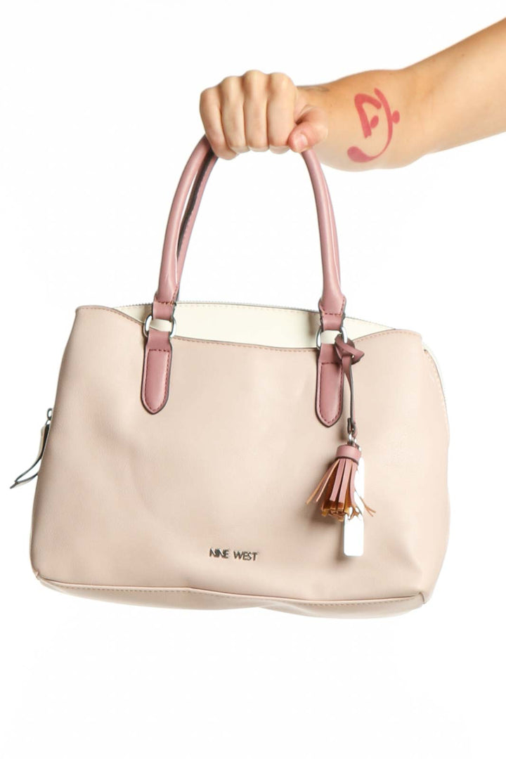 Cream leather shoulder bag by Nine West with pink handles and tassel detail, front view