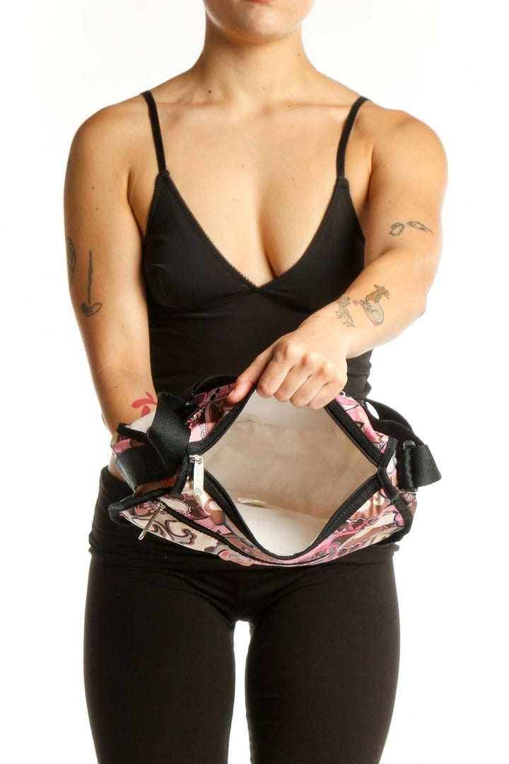 Pink paisley Lesportsac crossbody bag worn as crossbody style with black strap, back view on model