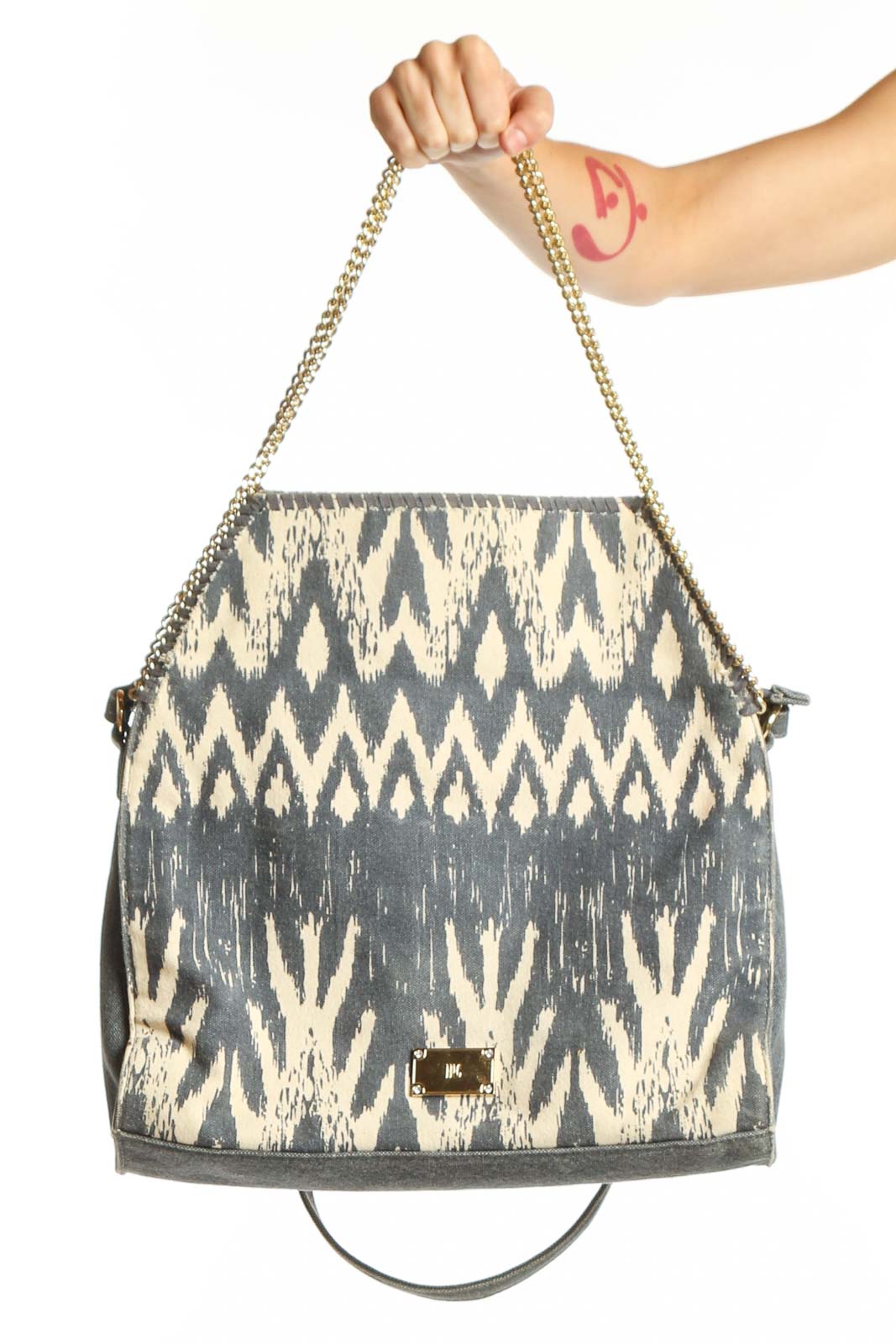 Gray and cream ikat patterned shoulder bag with chain straps held in hand