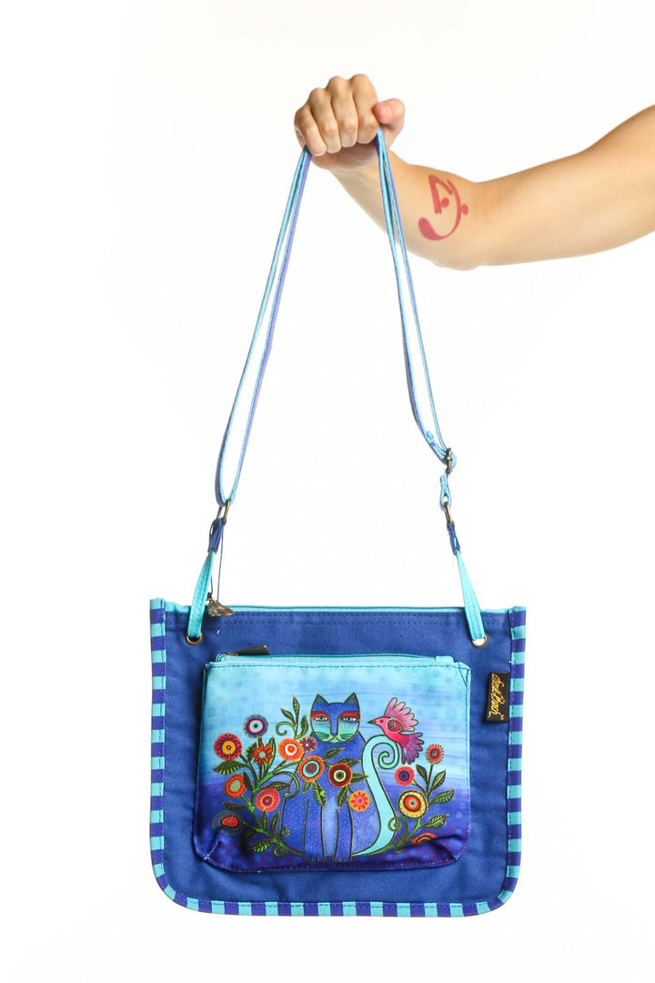 Blue canvas crossbody bag with whimsical floral cat illustration and checkered border pattern