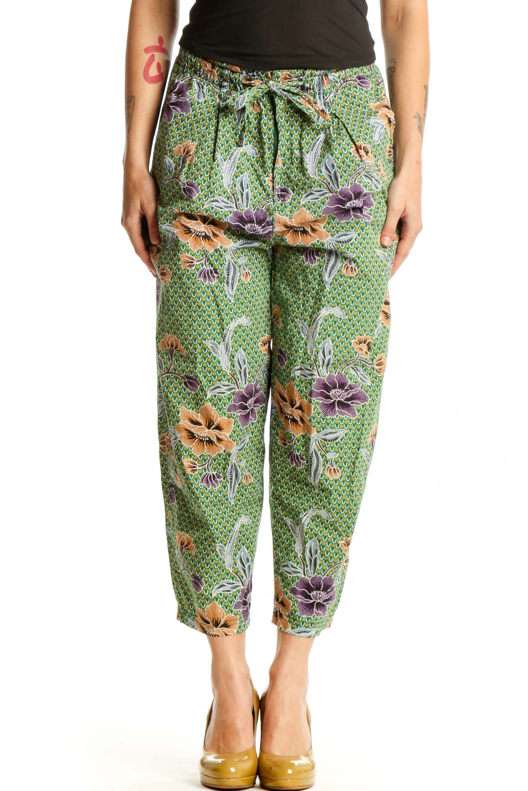 Front view of green floral cropped pants with purple and orange botanical print, drawstring waist, and side pockets