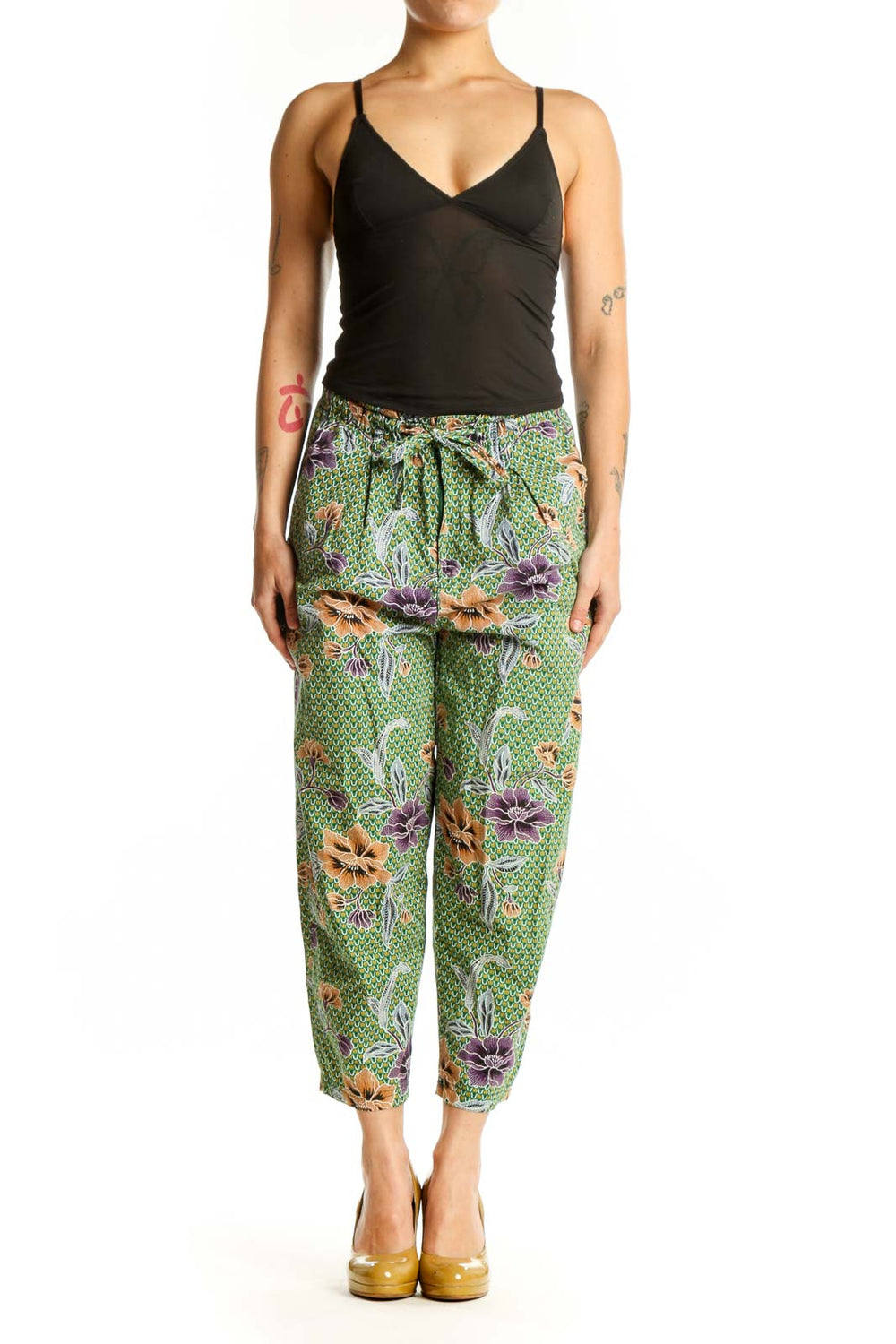 Front view of green floral cropped pants with purple and orange botanical print, drawstring waist, and side pockets