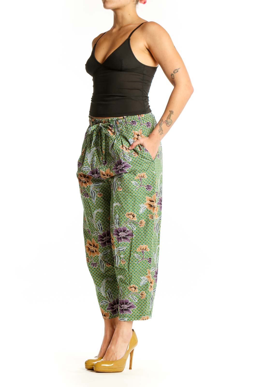 Front view of green floral cropped pants with purple and orange botanical print, drawstring waist, and side pockets