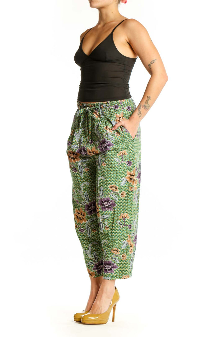 Front view of green floral cropped pants with purple and orange botanical print, drawstring waist, and side pockets