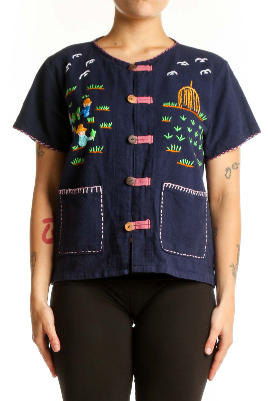 Navy SilkRoll embroidered button-up top with colorful hand-stitched designs including children, suns, and grass motifs, coral buttons, and white stitched patch pockets