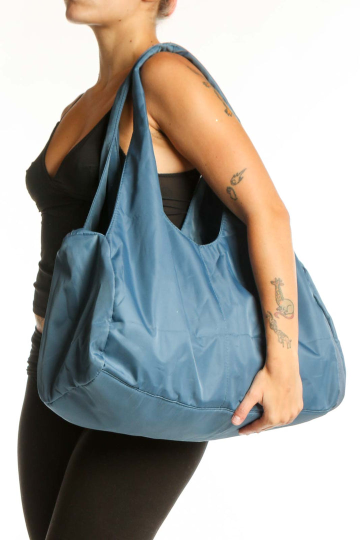 SilkRoll blue slouchy hobo tote bag held by hand, showing front view with dual shoulder straps