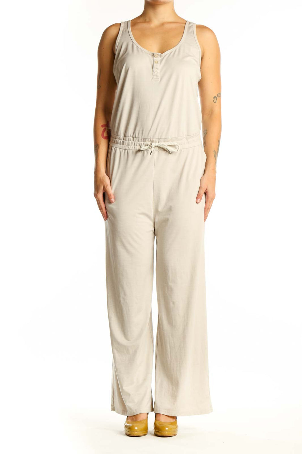 Front view of cream sleeveless jumpsuit with scoop neckline, button-front closure, and drawstring waist