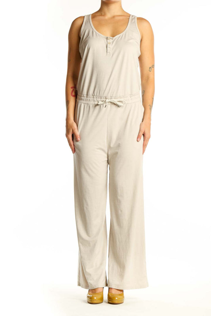 Front view of cream sleeveless jumpsuit with scoop neckline, button-front closure, and drawstring waist