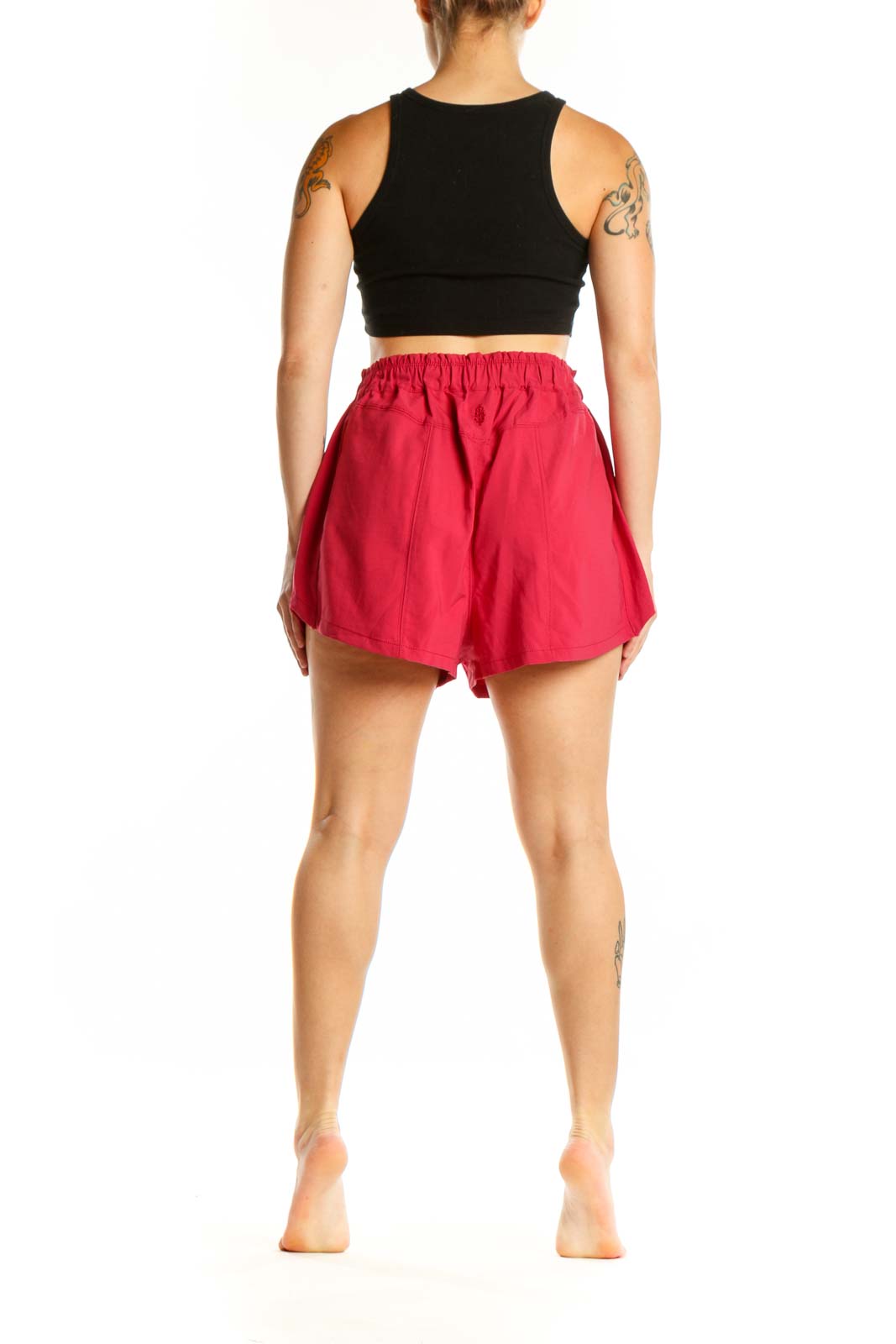 Red athletic shorts with mesh pockets, side view showing relaxed fit and length