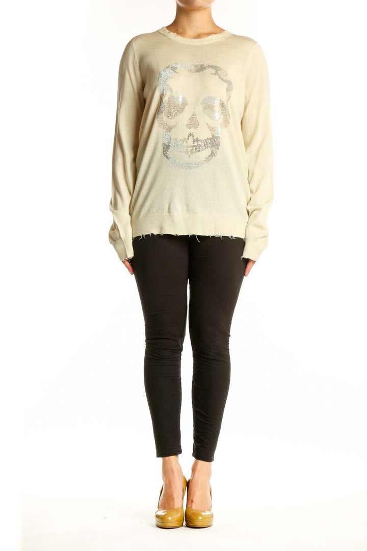 Cream merino wool sweater with shimmering silver skull graphic on front, distressed hem detail