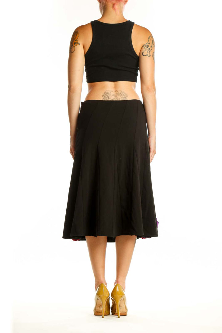 Black flare skirt with colorful floral embellishments, back view showing pleated waist and A-line silhouette