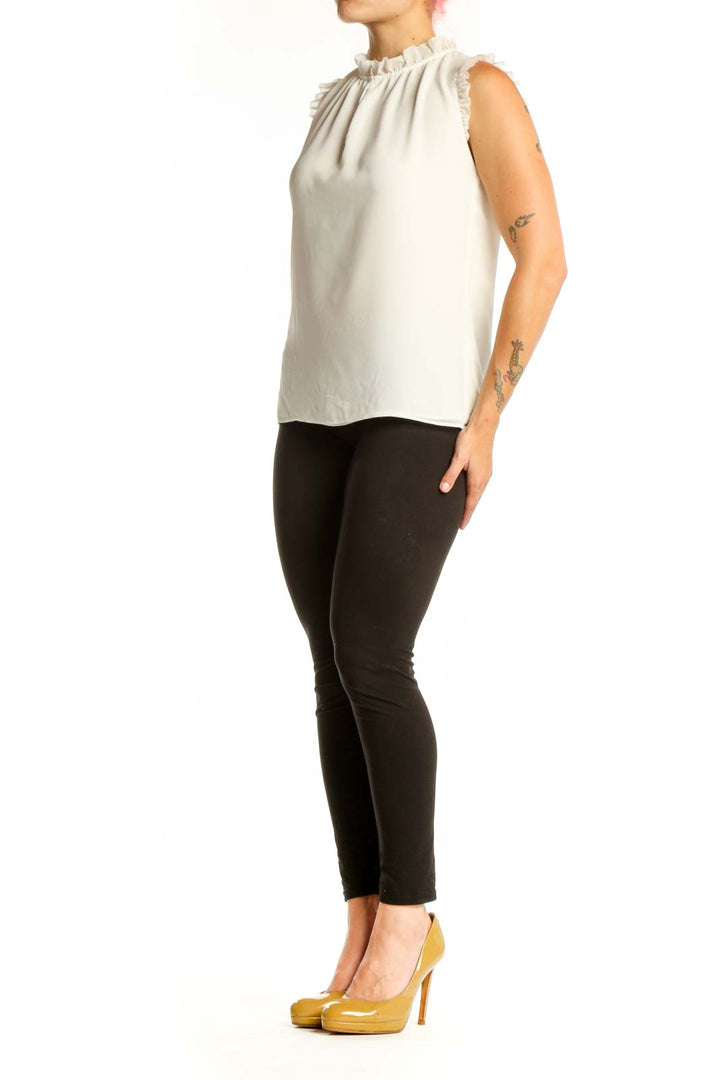 Cream sleeveless top with ruffle shoulder details and crew neckline, front view