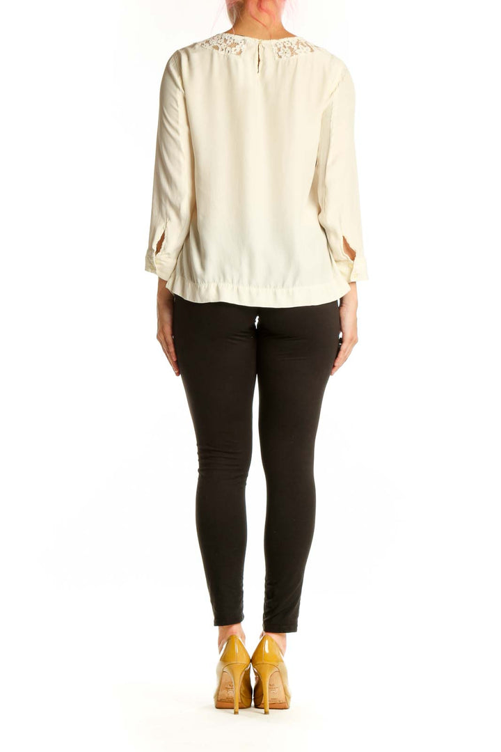 Cream Sandro blouse with lace neckline detail, back view on model