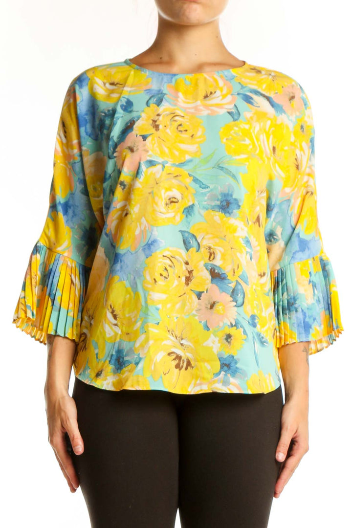 Yellow floral pleated bell sleeve top by Sioni with blue and coral flowers, worn with black pants