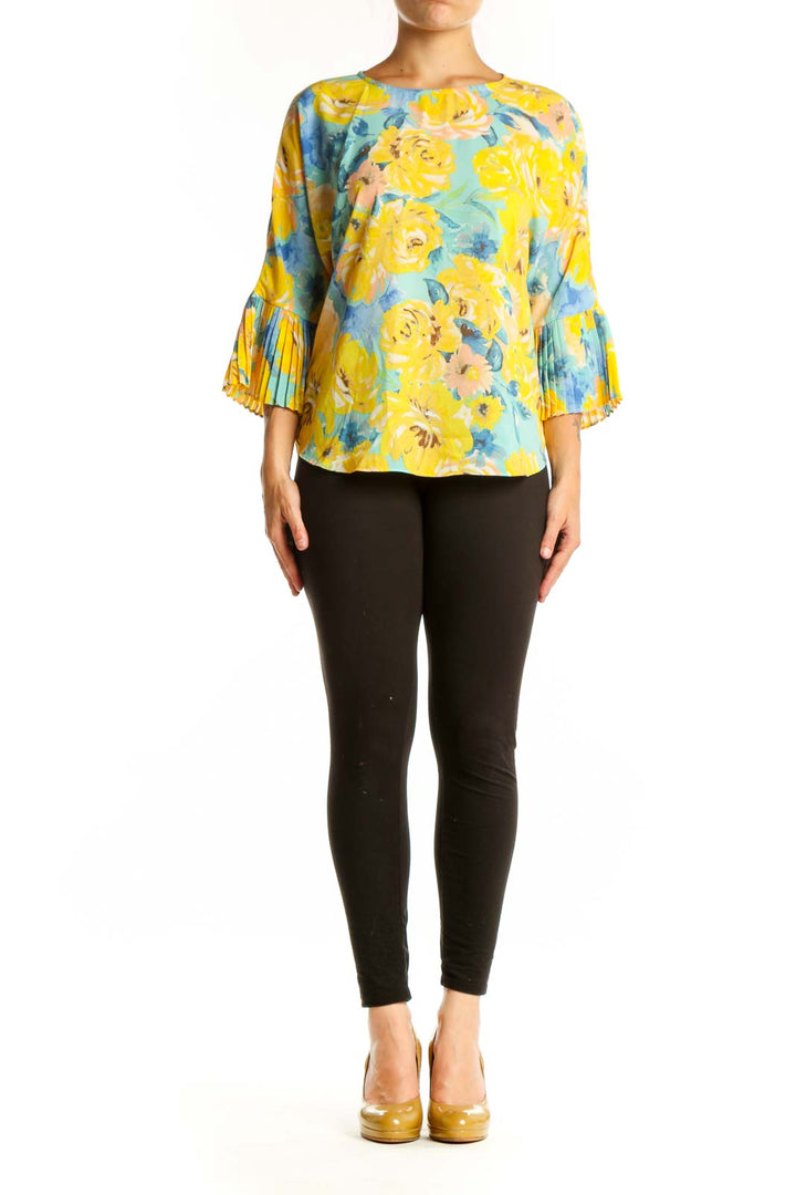 Yellow floral pleated bell sleeve top by Sioni with blue and coral flowers, worn with black pants