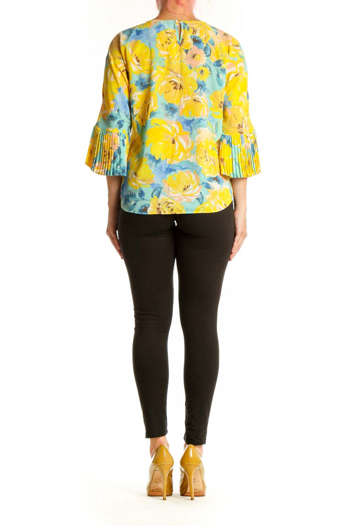 Back view of yellow floral Sioni top showing pleated bell sleeves and relaxed fit silhouette