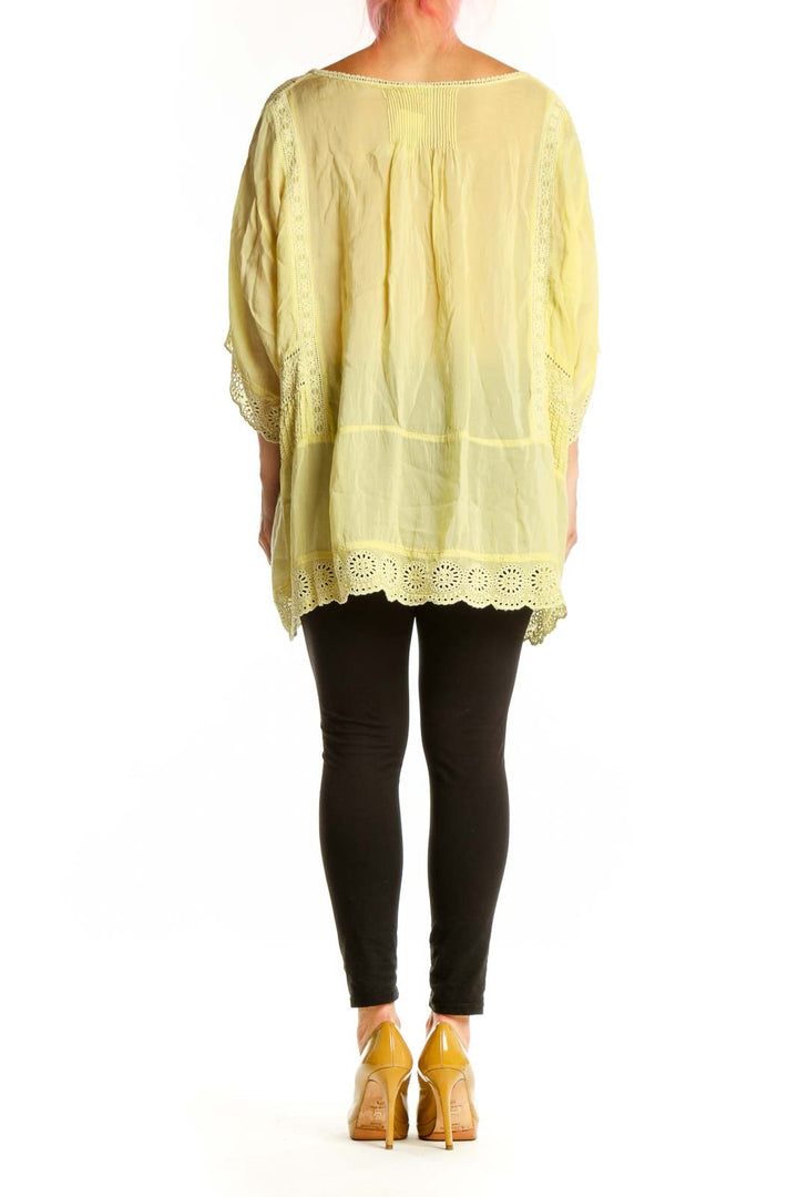 Back view of pale yellow embroidered tunic top showing relaxed fit and cutout sleeve details