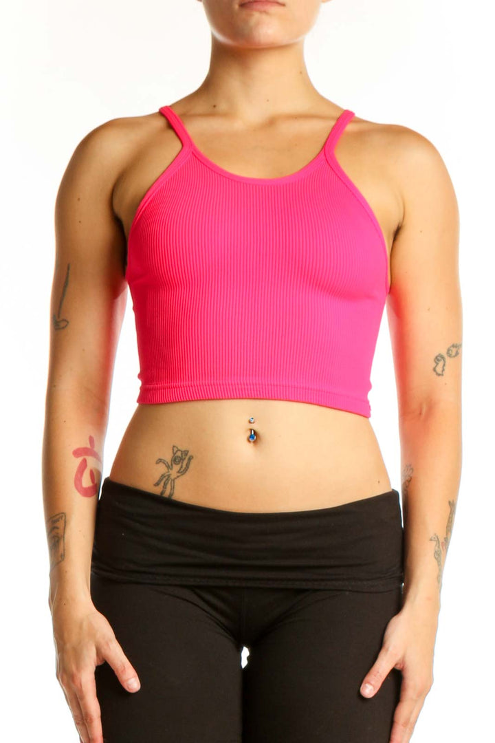 Woman wearing pink ribbed crop tank top with racerback design and black leggings, front view
