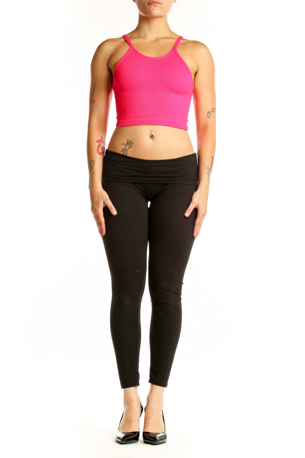Woman wearing pink ribbed crop tank top with racerback design and black leggings, front view
