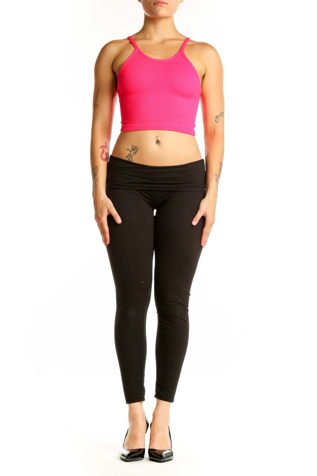Woman wearing pink ribbed crop tank top with racerback design and black leggings, front view