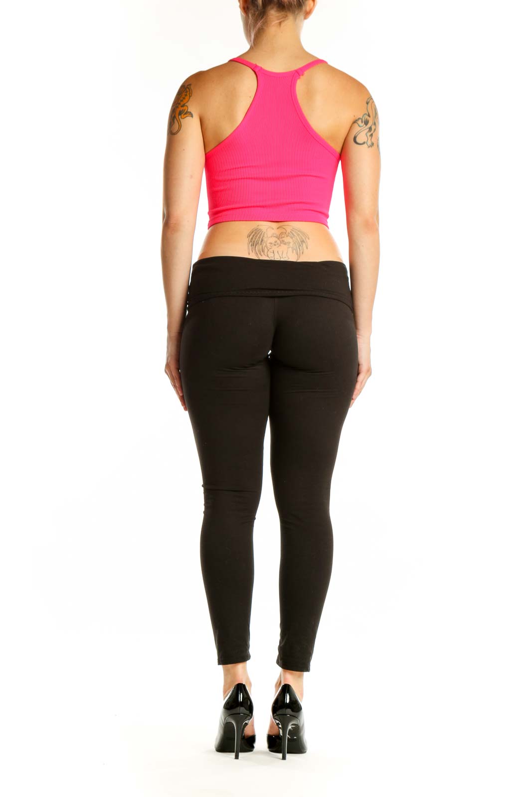 Woman wearing pink ribbed crop tank top with racerback design and black leggings, back view