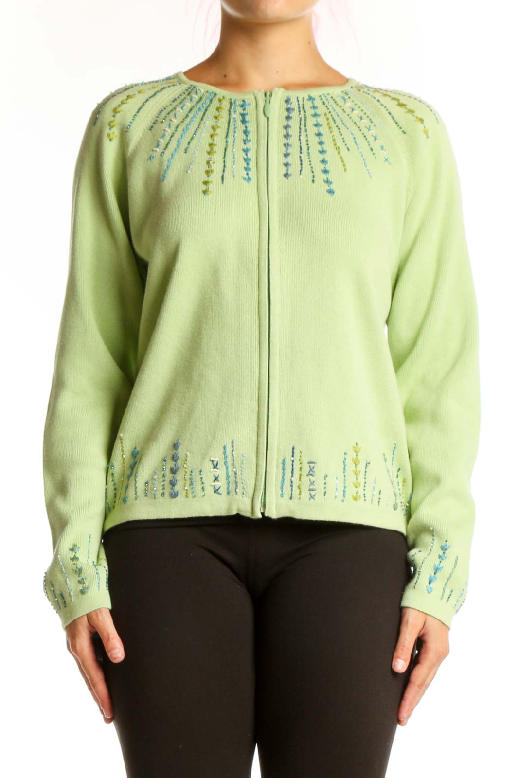 Lime green cotton cardigan with embroidered teal and blue details on neckline and cuffs, worn with black pants