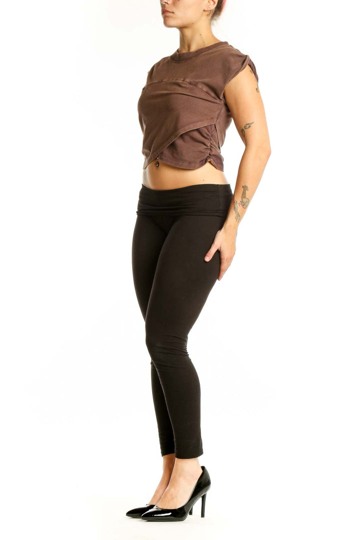 Brown twisted crop tank top with asymmetrical front design, paired with black leggings