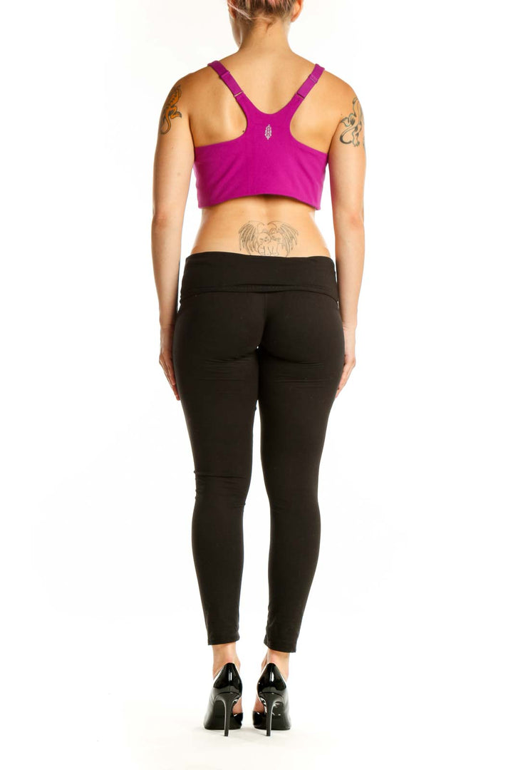 Woman wearing magenta sports bra with black leggings, back view showing crop top design
